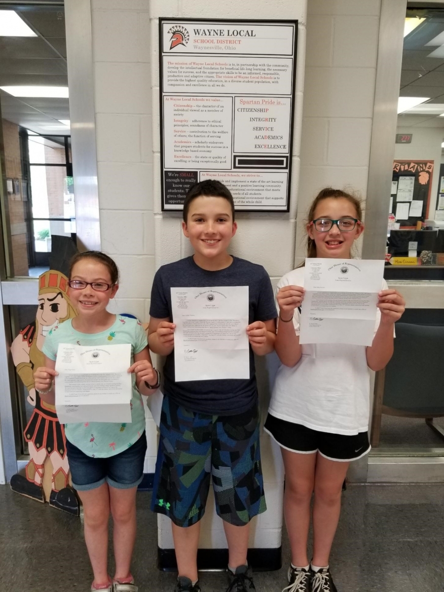 three students holding paper